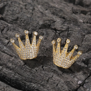 Gros plan de boucles d'oreilles couronne dorées avec zircons blancs sur fond charbon