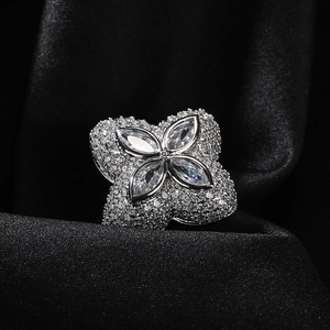 Makroaufnahme eines vierblättrigen Blumenrings mit Zirkonia und Pavé-Diamanten auf schwarzer Seide