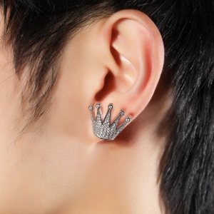 Gros plan détaillé d'une boucle d'oreille couronne en argent avec zircons blancs sur l'oreille