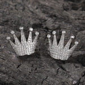 Gros plan sur les boucles d'oreilles couronne en argent avec zircons sur fond de pierre