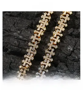 Macro detail of gold hip hop necklace featuring iced-out diamond cross links on black wood