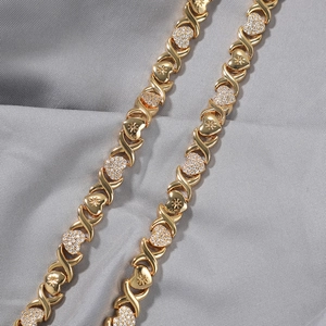 Macro detail of gold heart and X links with sparkling cubic zirconia on gray texture