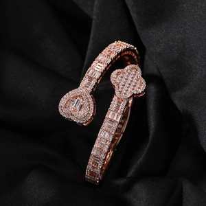 Macro view of rose gold open bangle with zircon heart and clover on black silk