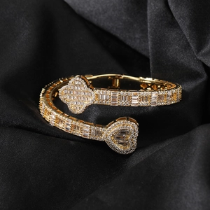 Detail of gold arm cuff with zircon clover and heart charms on black silk