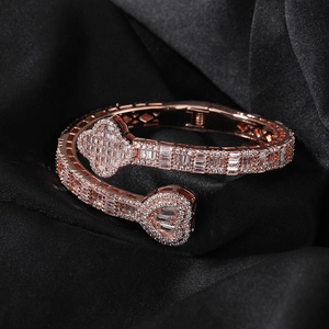 Close-up of rose gold clover and heart bangle with cubic zirconia on black satin