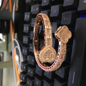 Detail of rose gold open bracelet with clover heart design and pavé stones on a keyboard
