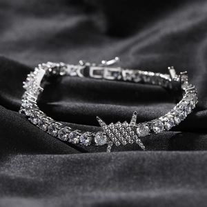Macro view of silver tennis bracelet with iced-out barbed wire charm on black satin