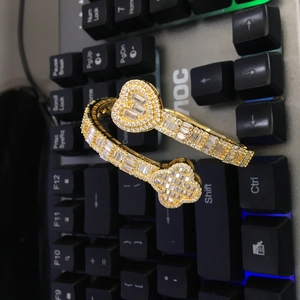 Close-up of hip hop gold open bangle with heart and clover iced out zircon details