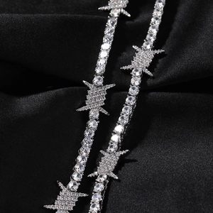 Macro shot of silver barbed wire necklace with pave-set cubic zirconia on black silk