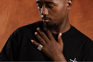 Dettaglio dell'anello hip hop numero 100 argento con zirconi sulla mano di un uomo