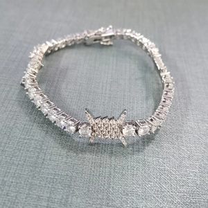 Close-up of silver-tone tennis bracelet with iced-out thorn charm and round-cut cubic zirconia