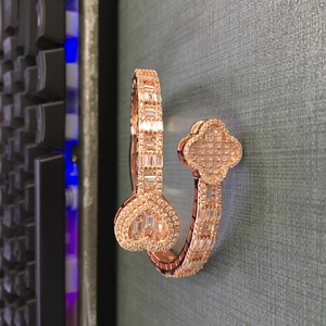 Close-up of rose gold cuff bracelet with sparkling zircon heart and clover charms