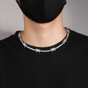 Detail of silver hip hop thorn necklace with cubic zirconia on black outfit