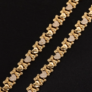 Macro shot of gold necklace with zircon bear and heart charms on black velvet