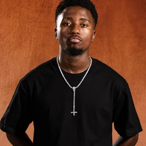 Hip hop style cross pendant necklace with zircon stones worn by a male model on a black tee