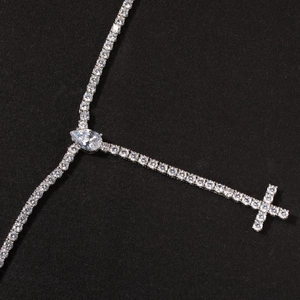Close-up of silver tennis chain necklace with pear-shaped stone and iced out cross pendant
