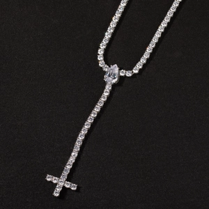 Macro view of silver Y-shaped tennis chain with drop stone and cross pendant