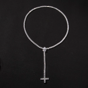 Macro detail of silver Y-shape tennis chain with teardrop stone and cross pendant