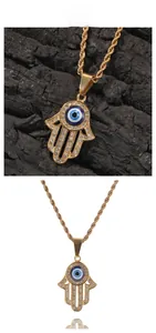 Dettaglio del ciondolo mano di Fatima dorata con occhio blu e pietre di zircone
