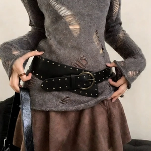 Détail d'une ceinture en cuir noir à rivets avec boucle en bronze sur tricot vintage