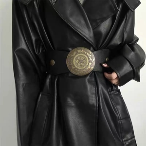 Detail of vintage bronze round buckle with floral patterns on wide black elastic waist belt