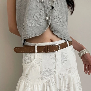 Detail of brown suede belt with double rows of silver rivets and a round pin buckle