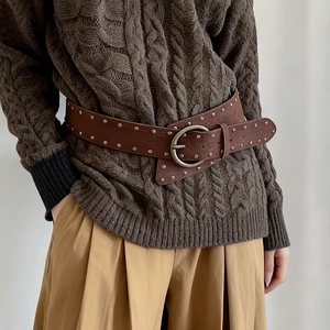 Détail de la large ceinture en cuir marron avec boucle ronde en argent et rivets