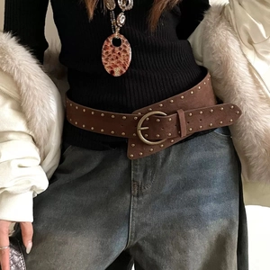 Gros plan sur une ceinture large en cuir marron vintage avec rivets et boucle ronde
