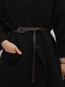 Détail d'une fine ceinture nouée marron foncé sur un blazer montrant le design sans boucle