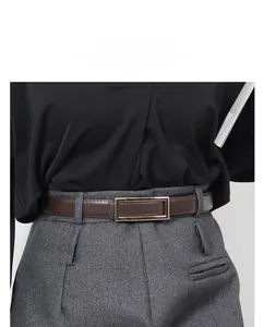 Close-up of a slim dark brown leather belt with a polished gold rectangular buckle on trousers
