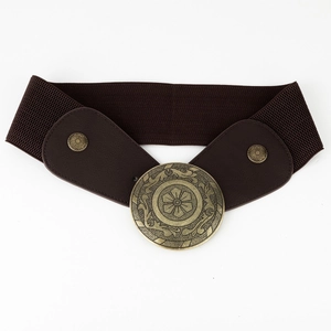 Detail of vintage brown elastic waist belt featuring a large embossed bronze buckle