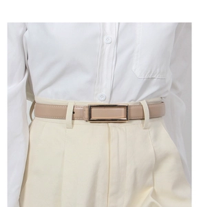 Detail of slim beige leather belt with a gold rectangular buckle on white office trousers