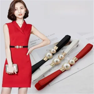 Close-up of elastic waist belts featuring large pearl buckles in black, white, and red