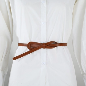 Détail d'une fine ceinture en cuir marron nouée en boucle sur une robe chemise blanche