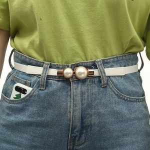 Detail of white elastic waist belt with double pearl buckle on denim jeans and green shirt