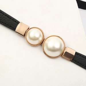 Macro detail of elastic belt with dual pearls and rose gold metal settings