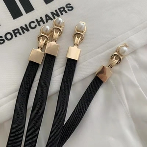 Close-up of four black elastic waist cincher clips with gold hardware and white pearl detail