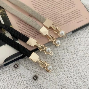 Detail of slim elastic waist belts with gold metal buckle and elegant pearl embellishment
