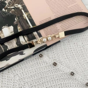 Close-up of black elastic waist belt with elegant gold double pearl buckle details