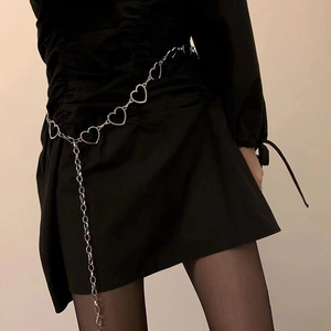 Detail view of heart-shaped silver metal chain belt styled on a black dress for women