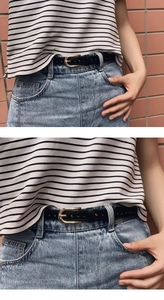 Close-up of black skinny leather belt with gold U-shape buckle on blue denim jeans