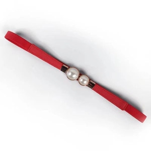 Detailed close-up of a red elastic waist belt with elegant gold-tone pearl buckle
