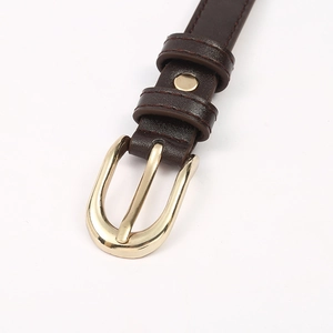Close-up of a slim dark brown leather belt with a polished gold pin buckle and fine stitching