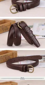 Detail view of a slim vintage leather belt with an antique gold pin buckle on wood