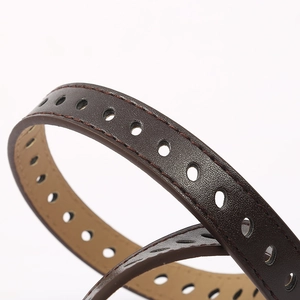 Close-up of thin brown leather belt with lychee texture and multiple punch holes
