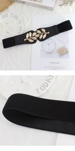 Close-up of golden leaf-shaped metal buckle on a black elastic waist belt for women