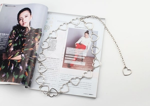 Macro shot of silver metal heart-shaped chain belt laid on a fashion magazine