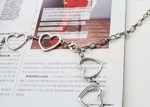 Detailed close-up of a silver heart-shaped metal waist chain with a lobster clasp