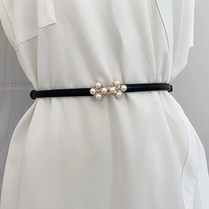 Détail de la boucle élégante en fleurs de perles sur une fine ceinture noire en cuir