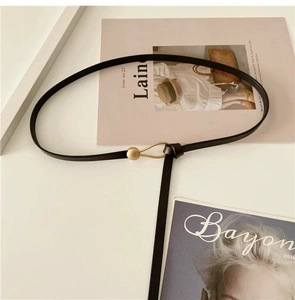 Detail of slim black leather belt with a unique matte gold ball hook buckle closure